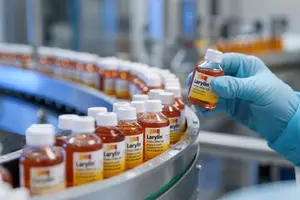 Mitarbeiter kontrolliert eine Flasche Larylin Hustensaft in der Abfüllanlage